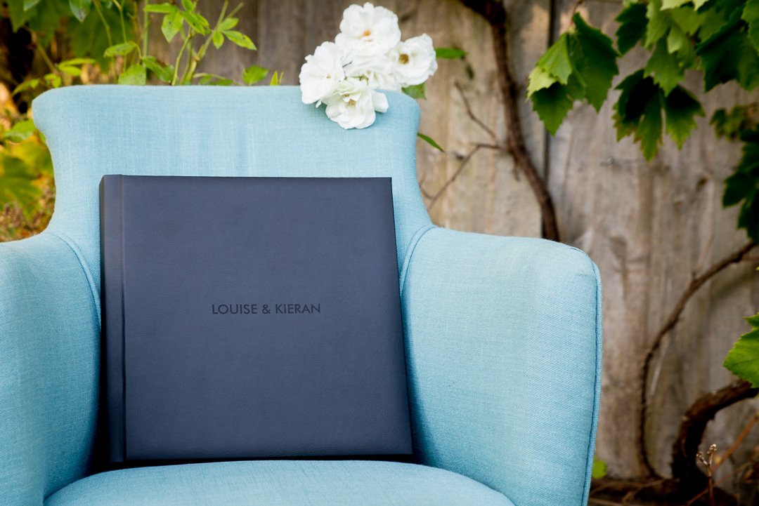navy blue wedding album propped up on a blue armchair