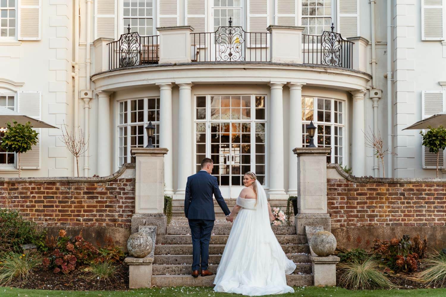 the bride and groom stop at the bottom of the steps into Gorse Hill and the bride looks back over her shoulder